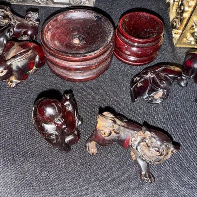 Sale Photo Thumbnail #269: Collection of carved amber-colored resin or lacquer animal figurines and wooden display stands, including foo dogs and rabbits.