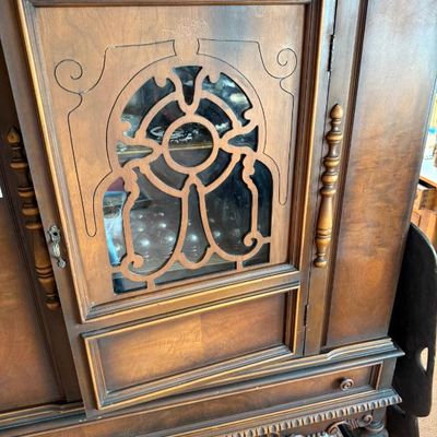 Sale Photo Thumbnail #258: Vintage dark stain wooden cabinet featuring an ornate glass door with decorative fretwork overlays and carved side trim.
