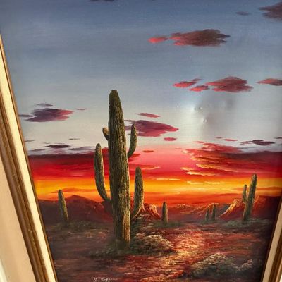 Sale Photo Thumbnail #82: Framed oil painting depicting saguaro cacti in a desert landscape at sunset, signed by the artist in the lower left.