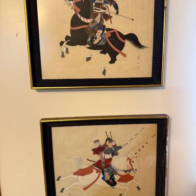 Sale Photo Thumbnail #123: Pair of framed Japanese woodblock prints depicting samurai warriors mounted on horses, set in black and gold frames.