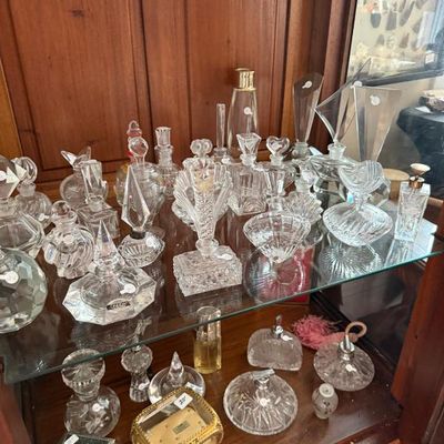 Sale Photo Thumbnail #253: Collection of vintage cut glass and crystal perfume bottles displayed in a wooden curio cabinet alongside decorative trinket boxes.