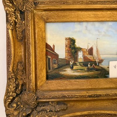 Sale Photo Thumbnail #69: Framed oil painting depicting a European coastal harbor scene with figures, ruins, and sailboat, set in an ornate carved gilt gesso frame.