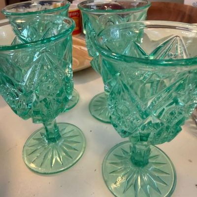 Sale Photo Thumbnail #312: Set of four vintage green pressed glass goblets featuring an ornate starburst and diamond pattern.