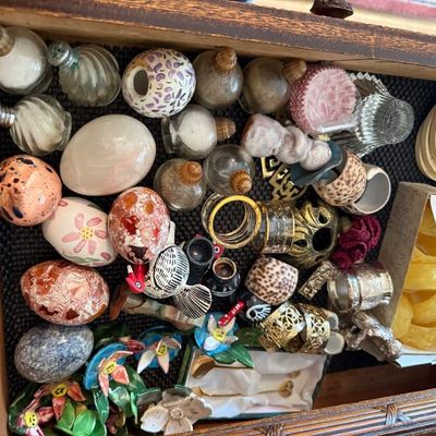 Sale Photo Thumbnail #320: Wooden drawer filled with a diverse collection of small trinkets, including decorative eggs, glass perfume bottles, napkin rings, and miniature figurines.