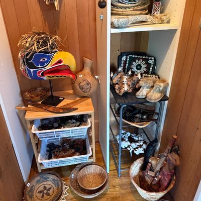 Sale Photo Thumbnail #236: Collection of Indigenous, Pacific Northwest, and global folk art items, including a painted eagle mask on a stand, carved boomerangs, woven baskets, and a kachina doll.