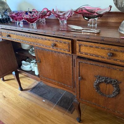 Sale Photo Thumbnail #153: Antique carved oak buffet sideboard with cabriole legs and detailed molding, topped with vintage cranberry art glass bowls and server pieces.