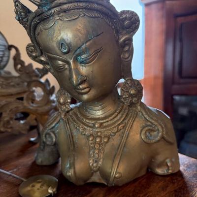 Sale Photo Thumbnail #351: Asian brass or bronze bust sculpture depicting a crowned deity, featuring ornate jewelry detailing and aged patina.
