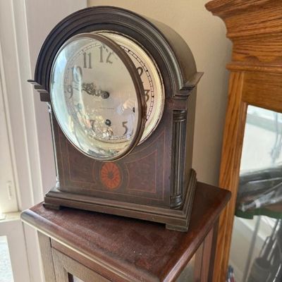 Sale Photo Thumbnail #356: Antique Seth Thomas wooden mantle clock featuring an arched case with inlaid details and a hinged glass door.