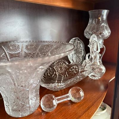 Sale Photo Thumbnail #331: Collection of vintage cut lead crystal glassware, including a large flared vase, small decanter, hurricane lamp, oval dish, and knife rest displayed inside a wooden cabinet.