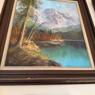Sale Photo Thumbnail #68: Framed oil landscape painting depicting a mountain peak reflecting in a calm lake, signed in the lower left corner and set in a dark wood frame with a linen liner.