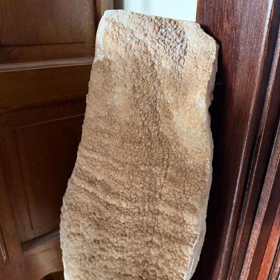 Sale Photo Thumbnail #134: Large natural quartz or calcite mineral slab specimen leaning against a wooden door frame, displaying a heavily textured crystalline surface.