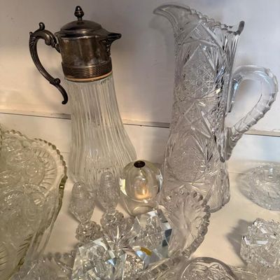 Sale Photo Thumbnail #304: Collection of vintage cut glass and crystal tableware, including a tall cut glass pitcher, a silver-plated glass claret jug, and various small serving pieces.
