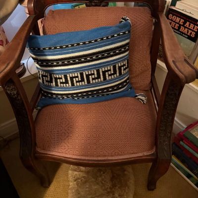Sale Photo Thumbnail #165: Antique carved wooden armchair featuring a shell crest rail and pink patterned upholstery, styled with a blue woven geometric throw pillow.