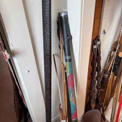 Sale Photo Thumbnail #222: Collection of decorative wooden items, including a painted didgeridoo, oversized carved wooden spoons, arrows, and wrapped staffs.