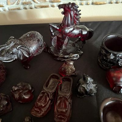 Sale Photo Thumbnail #268: Collection of carved faux amber and resin decorative objects, including figurines of a horse, an elephant, small shoes, and various Asian-inspired trinkets.