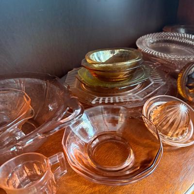 Sale Photo Thumbnail #336: Collection of vintage pink and amber depression glass tableware, including plates, small bowls, a cream pitcher, and a citrus juicer.