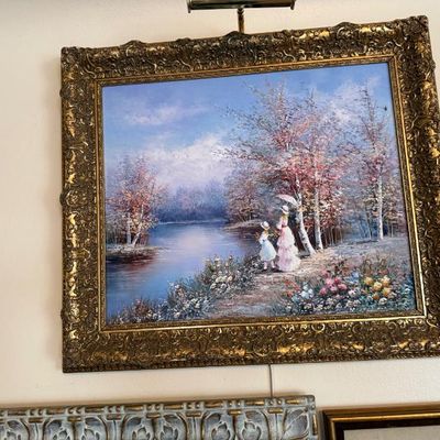 Sale Photo Thumbnail #96: Impressionist-style oil painting depicting a woman and child strolling along a lakeside path, presented in an ornate gilt wood frame.