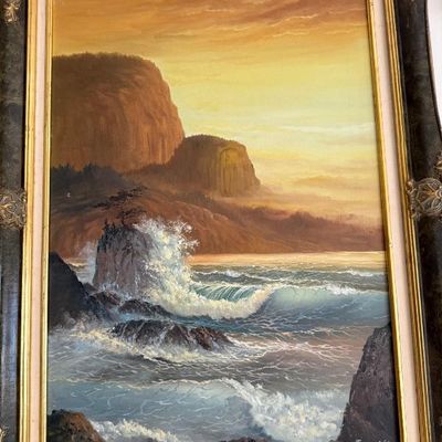 Sale Photo Thumbnail #62: Framed vintage oil painting depicting a dramatic coastal seascape with crashing waves and rocky cliffs, housed in an ornate dark wooden frame with gold trim.