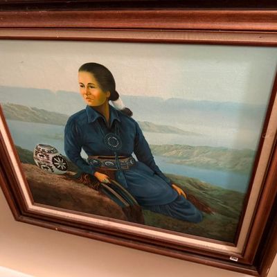 Sale Photo Thumbnail #59: Framed oil painting depicting a Native American woman seated in a landscape with pottery, housed in a double-matted wood frame.