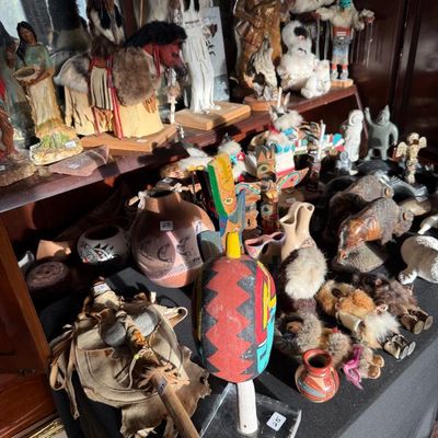 Sale Photo Thumbnail #207: Collection of Native American themed collectibles, featuring kachina dolls, carved wooden figures, pottery, miniature totem poles, and fur-dressed dolls.