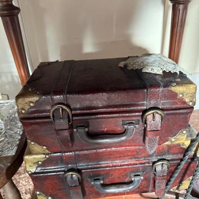 Sale Photo Thumbnail #196: Pair of decorative vintage-style miniature trunk boxes featuring reddish faux leather finish, brass corner brackets, buckle straps, and top handles.