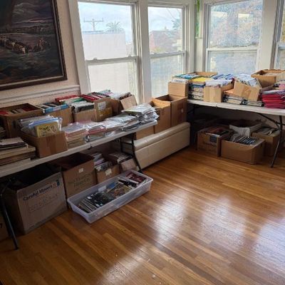 Sale Photo Thumbnail #192: Large collection of comic books and media items organized in cardboard boxes and plastic totes on folding tables and floor.