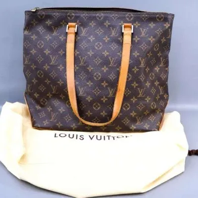 Vintage Louis Vuitton Monogram Luco tote bag with natural leather handles, resting on a branded cream dust bag.