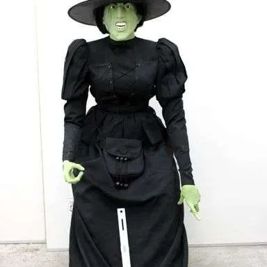 Life-sized Wicked Witch of the West prop figure featuring a detailed green mask, pointed black hat, and black gown.