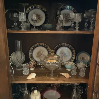 Sale Photo Thumbnail #4: Wooden hutch filled with vintage glassware, porcelain plates with cobalt and gold rims, crystal stemware, and decorative seashells.