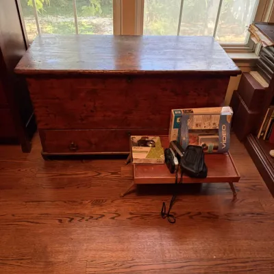 Sale Photo Thumbnail #124: Antique wooden blanket chest with a bottom drawer, paired with small electronics and boxed items set on a tray in front.