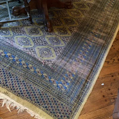 Sale Photo Thumbnail #38: Hand-knotted Persian-style wool area rug featuring geometric patterns and diamond motifs in blue, yellow, and tan tones, showing moderate wear and fringe fraying.