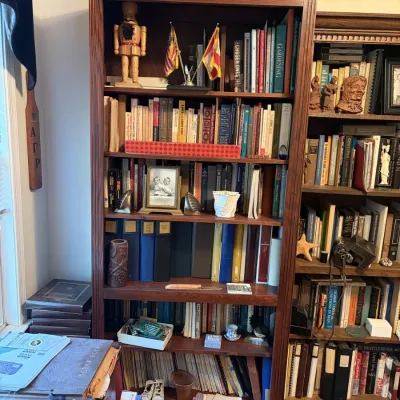 Sale Photo Thumbnail #94: Tall dark wood bookcase filled with books, small decorative items, framed photos, and a nutcracker.