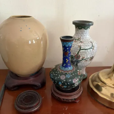 Sale Photo Thumbnail #63: Collection of Asian decorative vases, including a glazed ovoid ceramic vessel on a wooden stand alongside two floral cloisonné miniature vases.