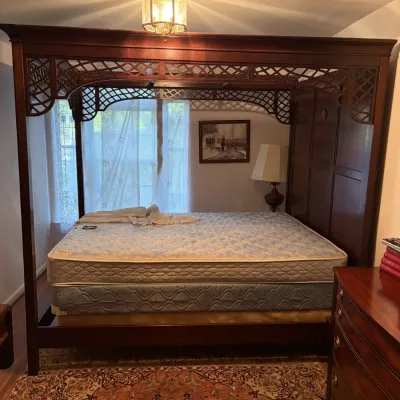 Sale Photo Thumbnail #78: Large dark wood canopy bed featuring intricately carved lattice frieze details and a paneled headboard.