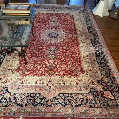 Sale Photo Thumbnail #13: Large Persian hand-knotted wool area rug featuring a central medallion with red, navy blue, and cream floral pattern motifs and fringed ends.