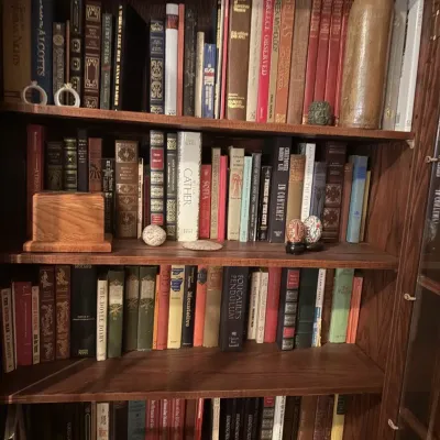 Sale Photo Thumbnail #47: Wooden bookcase filled with a varied collection of hardcover books, small wooden boxes, and decorative knick-knacks.