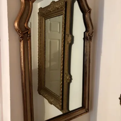 Sale Photo Thumbnail #88: Vintage wall mirror in a molded bronze-tone frame, reflecting a second ornate gilt frame mirror mounted on an adjacent wall.