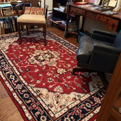 Sale Photo Thumbnail #126: Home office study featuring an oriental wool area rug with a central medallion, paired with a wooden writing desk, leather armchair, and accent chair.