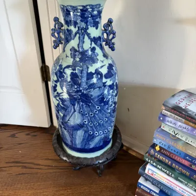 Sale Photo Thumbnail #119: Large Chinese blue and white ceramic floor vase featuring peacock motifs and ornate handles, resting on a carved dark wood stand.