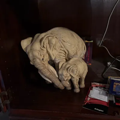 Sale Photo Thumbnail #52: Vintage resin figurine depicting a mother elephant with her calf, displayed inside a wooden cabinet.
