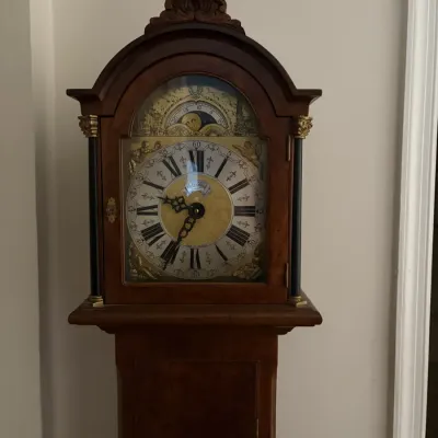 Sale Photo Thumbnail #71: Traditional wooden grandfather clock featuring a detailed brass face with Roman numerals, ornate spandrel accents, and a moon phase dial.