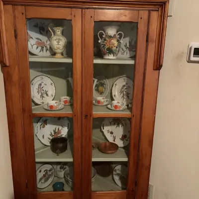 Sale Photo Thumbnail #50: Vintage pine corner display hutch with glass panel doors, housing various floral ceramics, teacups, and serving platters.