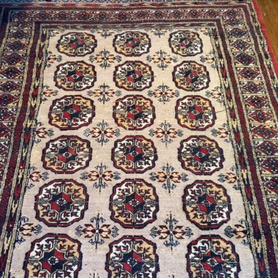 Sale Photo Thumbnail #120: Hand-knotted Bukhara wool area rug with geometric gul motifs in red, navy, and cream tones.