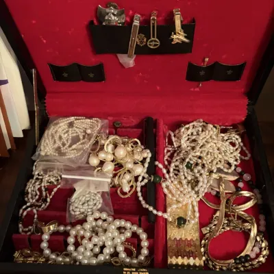 Sale Photo Thumbnail #85: Open red velvet-lined vintage jewelry box filled with costume jewelry, including pearl strands, gold-tone chains, and tie clips.