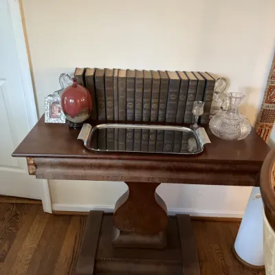 Sale Photo Thumbnail #17: Antique pedestal table displaying a set of leather-bound books, silver tray, cut glass decanter, and ceramic art vase.