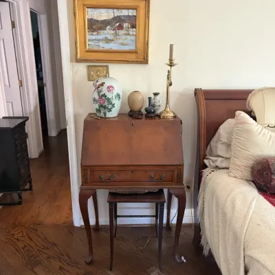 Sale Photo Thumbnail #62: Vintage Queen Anne style slant-top secretary desk with cabriole legs, paired with small accent stool and decor including Asian ceramics and framed winter landscape art.
