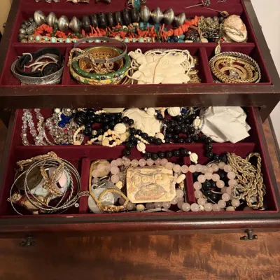 Sale Photo Thumbnail #82: Wooden jewelry chest filled with an assortment of vintage costume jewelry, including beaded necklaces, bangles, rings, and carved pendants.