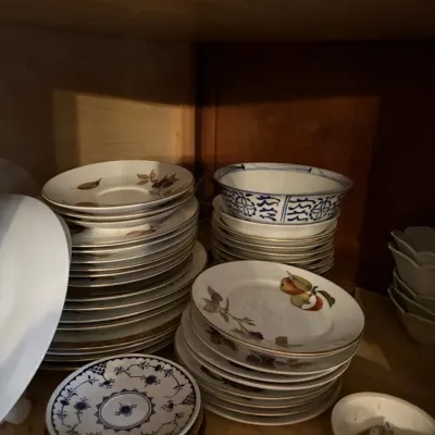 Sale Photo Thumbnail #36: Collection of porcelain tableware, including stacks of fruit-patterned plates, blue-and-white bowls, and saucers stored in a cabinet.