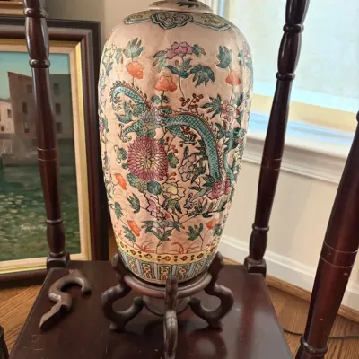 Sale Photo Thumbnail #8: Chinese Famille Rose porcelain temple jar, featuring detailed dragon and floral motifs with raised texture, resting on a carved wooden display stand.