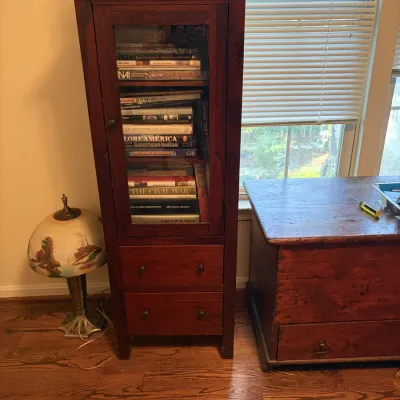 Sale Photo Thumbnail #91: Tall dark wood display cabinet with a glass front door and two lower drawers, filled with books.